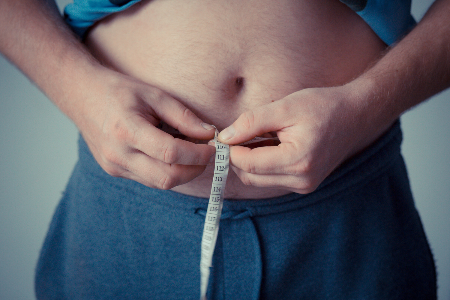 Person Holding Measuring Tape Around His Body