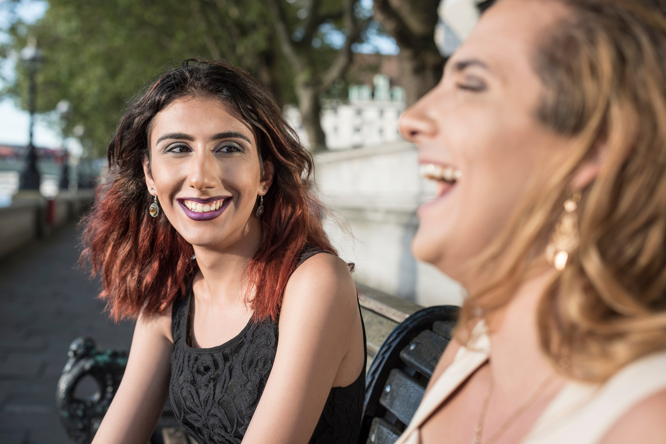 Two transgender female friends laughing outdoors